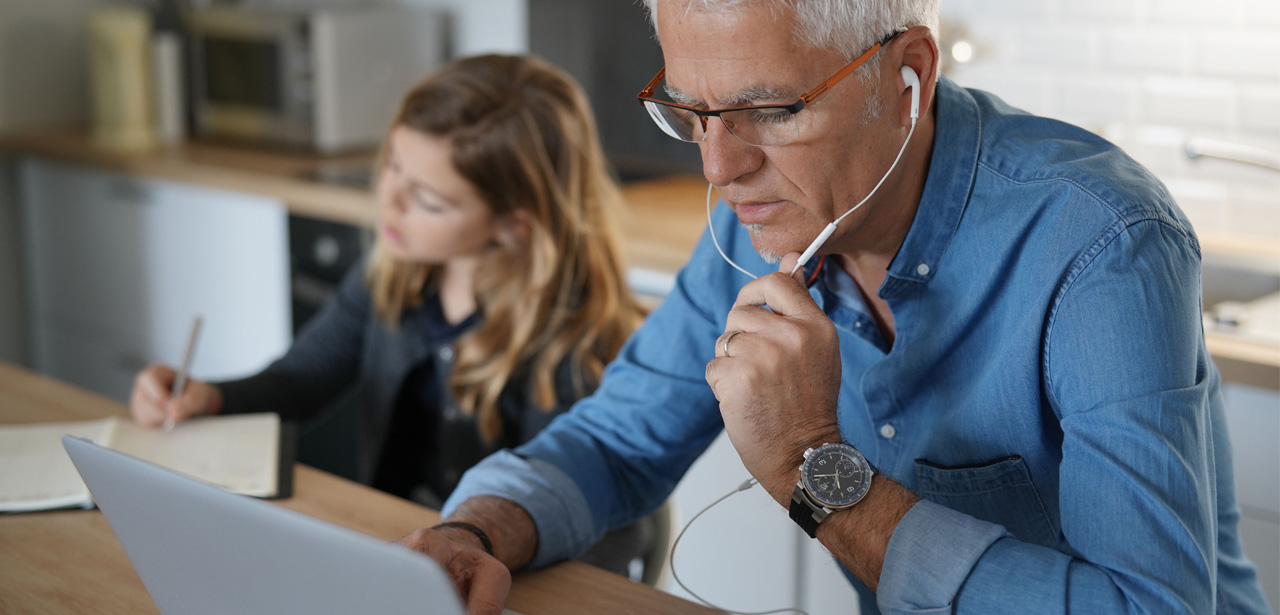 Visuel d'un père télé-travaillant à côté de son enfant à ses devoirs scolaires