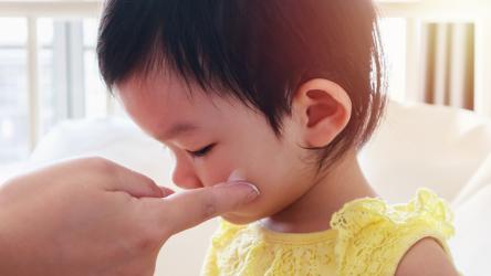 Un adulte applique une crème anti moustique sur le visage d'un jeune enfant