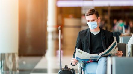 homme à l'aéroport portant un masque chirurgical en attendant son vol