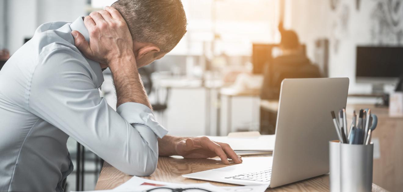 Photographie d'un homme souffrant de cervicalgie au travail