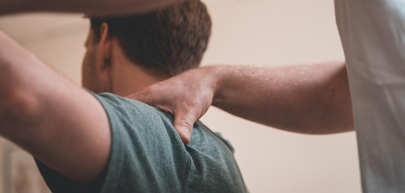 Patient en train de se faire manipuler l'épaule par un professionnel de santé