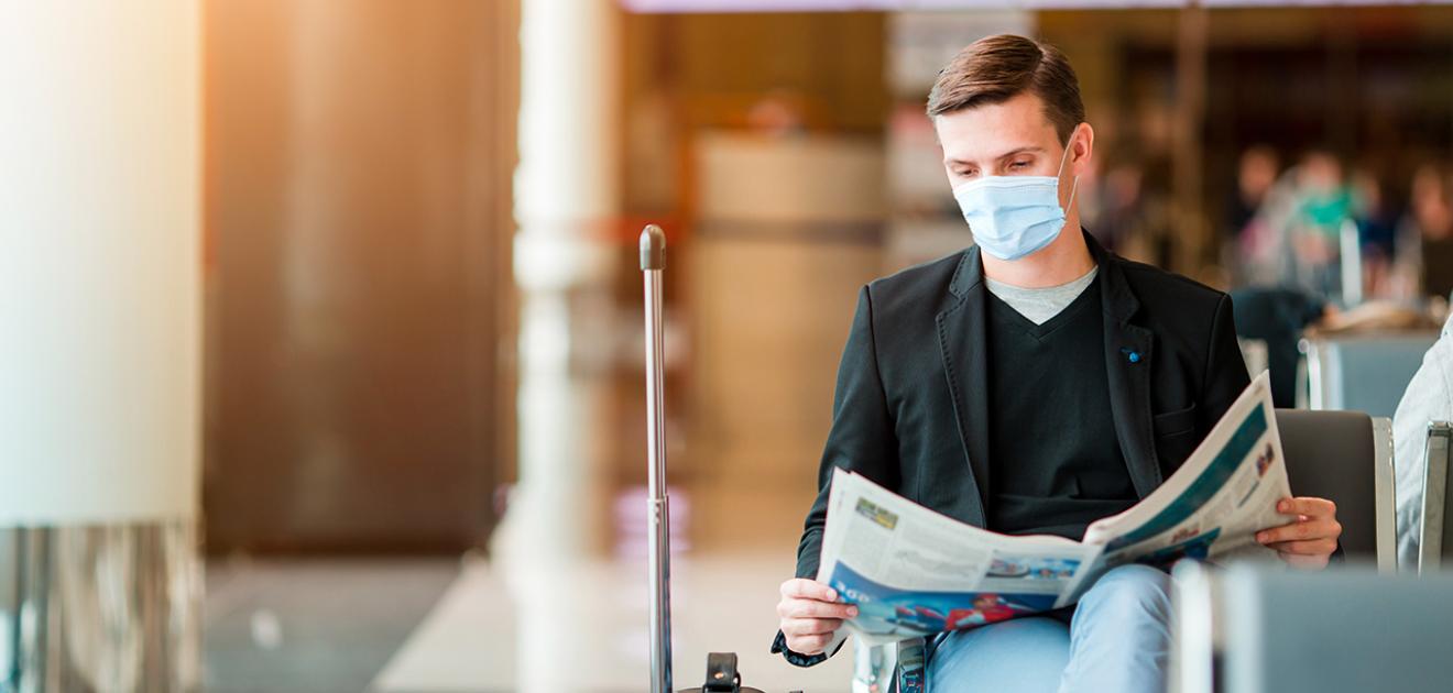 homme à l'aéroport portant un masque chirurgical en attendant son vol