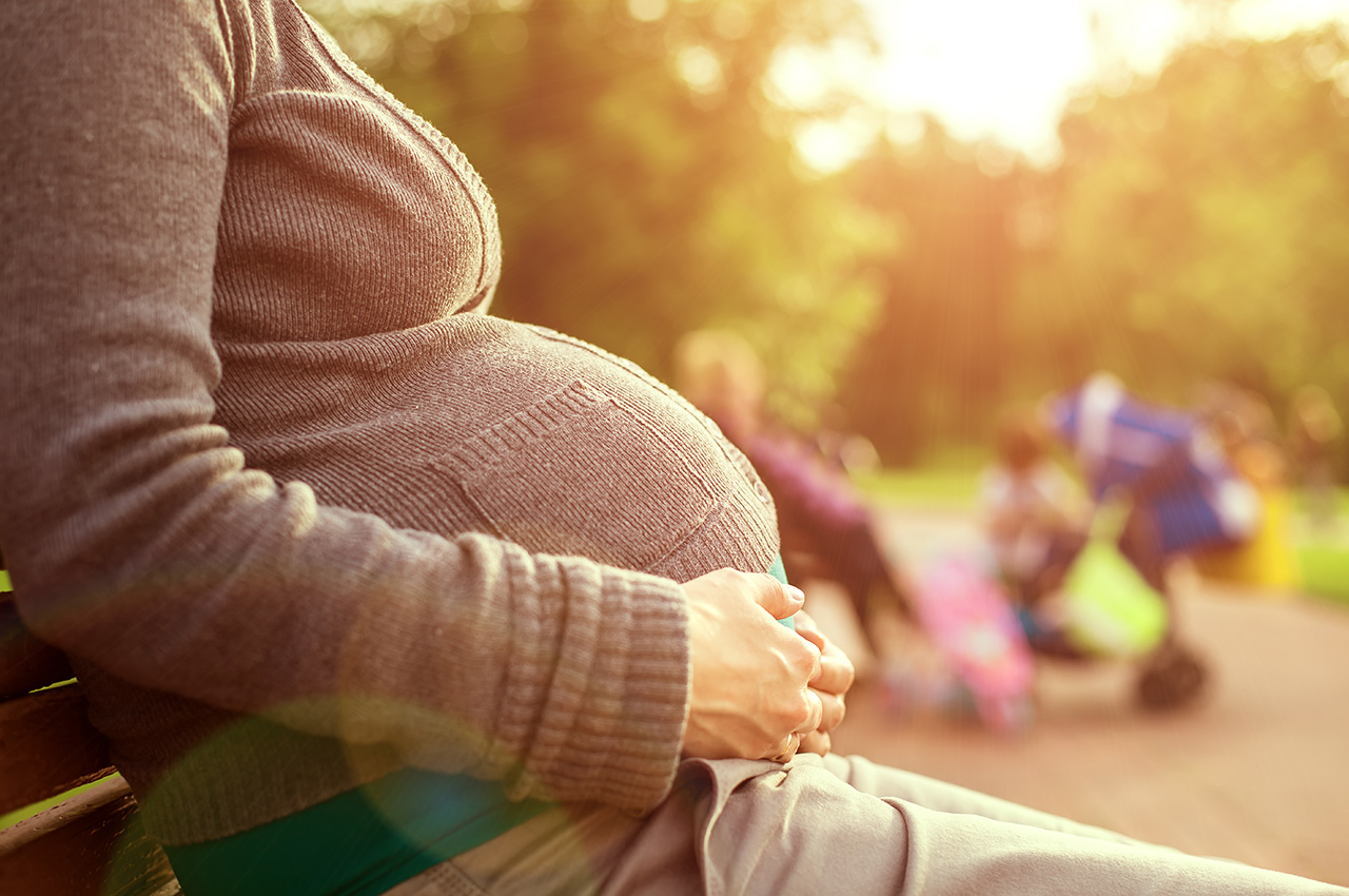 visuel personne enceinte assise sur un bac dans un parc
