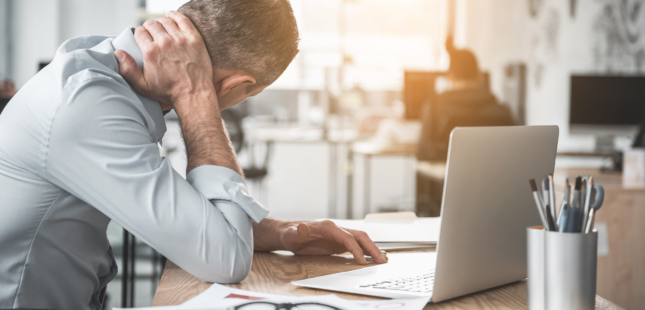 Photographie d'un homme souffrant de cervicalgie au travail