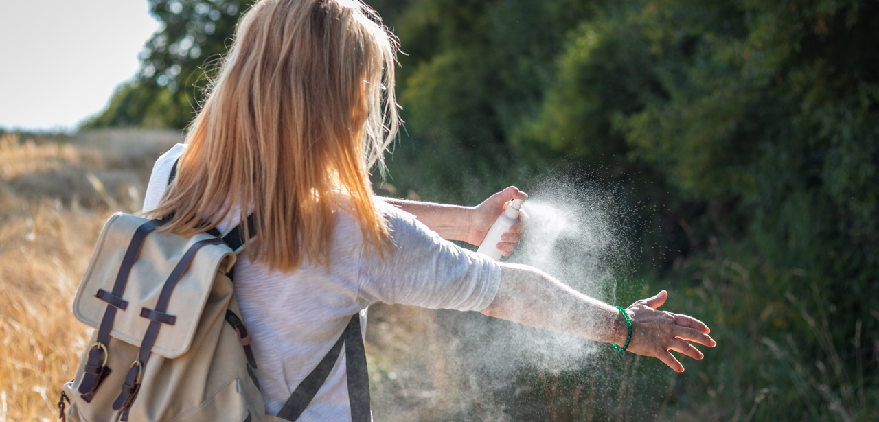 Photographie d'une femme s'aspergeant de répulsif anti-moustique