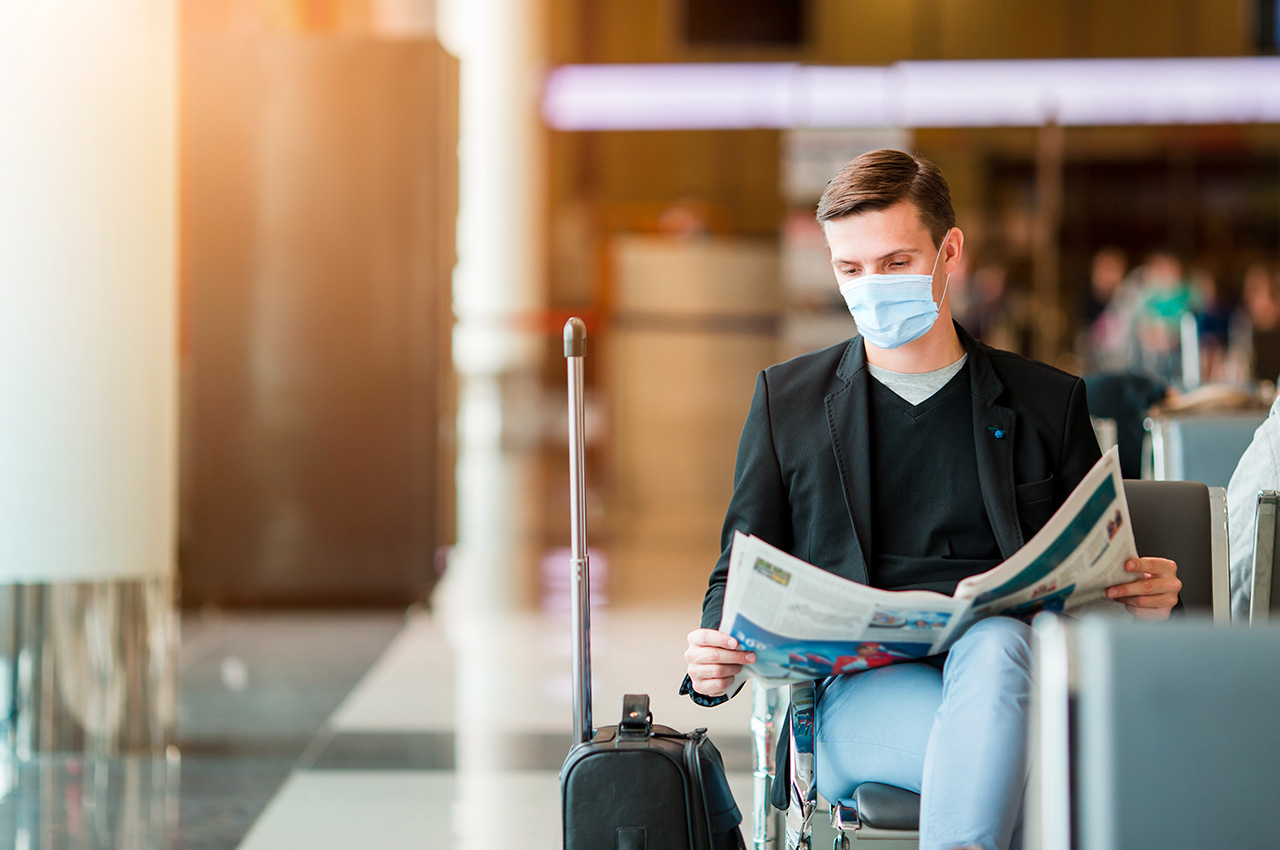 homme à l'aéroport portant un masque chirurgical en attendant son vol
